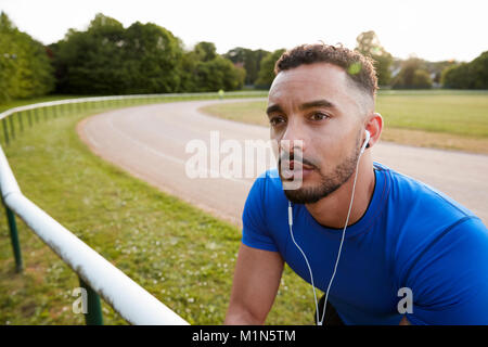 Voce maschile atleta che indossa gli auricolari alla via di corsa, close up Foto Stock