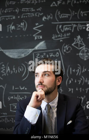 Giovane uomo contemplaiting davanti di Blackboard Foto Stock