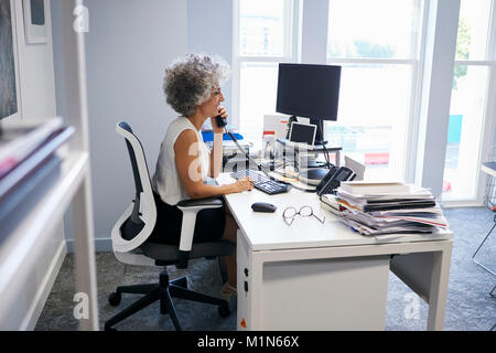 Persone di mezza età imprenditrice utilizzando il telefono nel suo ufficio Foto Stock
