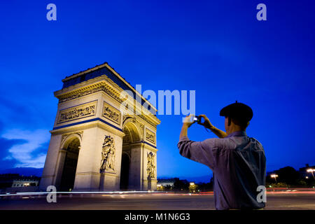 La Francia. Parigi. Uomo di scattare una foto di Arc de Triomphe. Crepuscolo. Foto Stock