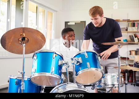 Pupilla d maschio con insegnante suonando la batteria In Lezione di musica Foto Stock