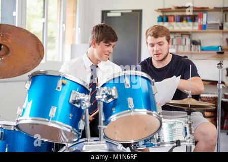 Pupilla d maschio con insegnante suonando la batteria In Lezione di musica Foto Stock