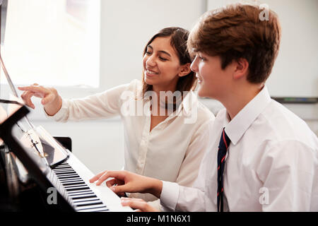 Pupilla d maschio con insegnante suonare il pianoforte nella lezione di musica Foto Stock