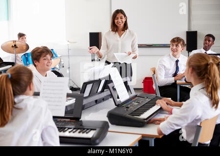 Gli studenti adolescenti studiano tastiera elettronica nella classe di musica Foto Stock