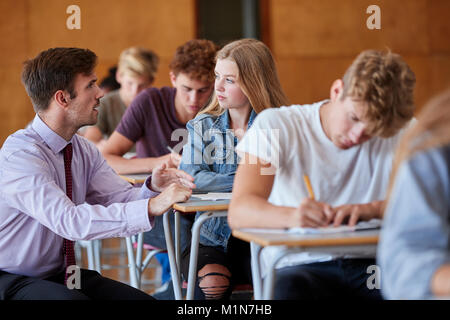 Gli studenti adolescenti seduta esame con insegnante Invigilating Foto Stock