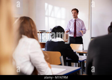 Gli studenti adolescenti ascoltando la voce maschile insegnante in classe Foto Stock