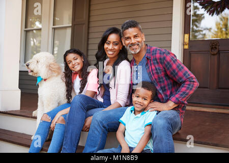 Famiglia con bambini e cane sedersi sui gradini di casa Foto Stock