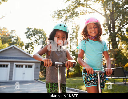 Fratello e Sorella in sella scooter sul vialetto a casa Foto Stock
