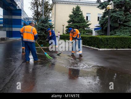 Simferopol, Russia - 15 Giugno 2016: portieri disperdere scope pozzanghere dopo la pioggia di fronte all'aeroporto di Simferopol Foto Stock