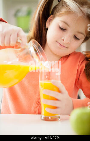 Una bambina bere un succo di frutta a casa Foto Stock