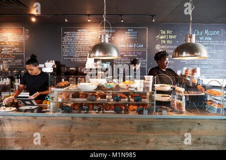 Il personale che lavora dietro il bancone in Busy Coffee Shop Foto Stock