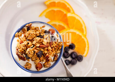 La colazione ciotola di muesli fatti in casa con yogurt, mirtilli freschi e fette di arance Foto Stock