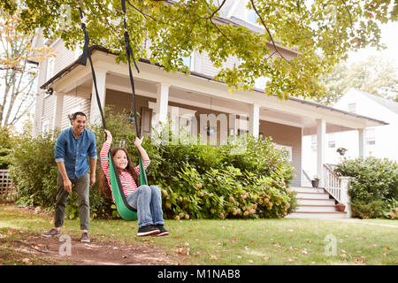 Padre Figlia di spinta su giardino Swing a casa Foto Stock