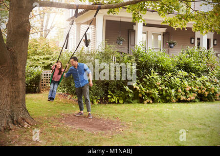 Padre Figlia di spinta su giardino Swing a casa Foto Stock