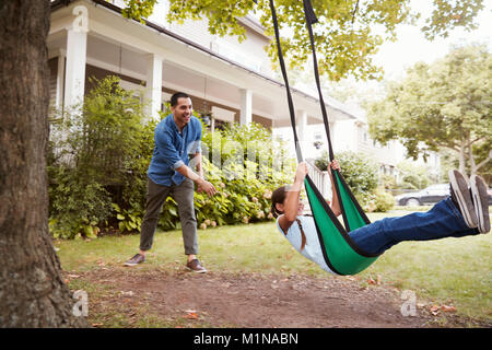 Padre Figlia di spinta su giardino Swing a casa Foto Stock