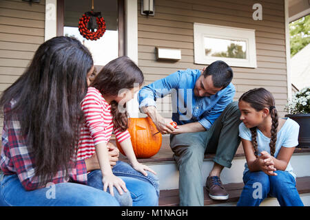 Famiglia Carving Zucca di Halloween sui gradini di una casa Foto Stock