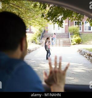 Padre In auto facendo scendere la figlia di fronte i cancelli della scuola Foto Stock