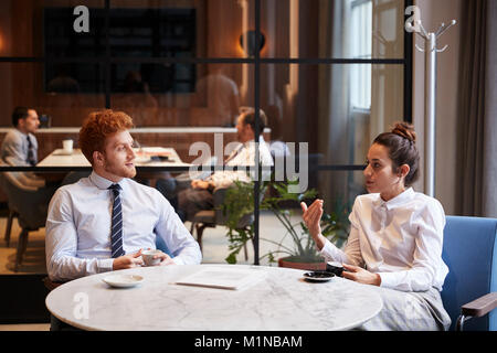Maschio e femmina i colleghi parlare in un caffè in ufficio cafe Foto Stock