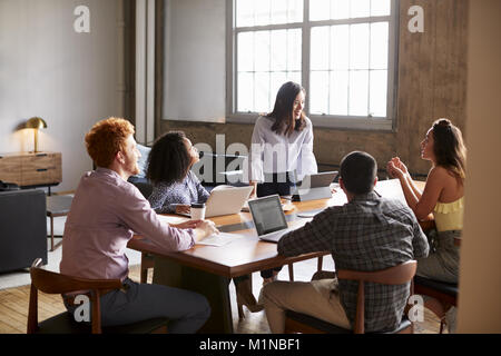 Giovane donna in piedi per affrontare i colleghi ad una riunione di lavoro Foto Stock