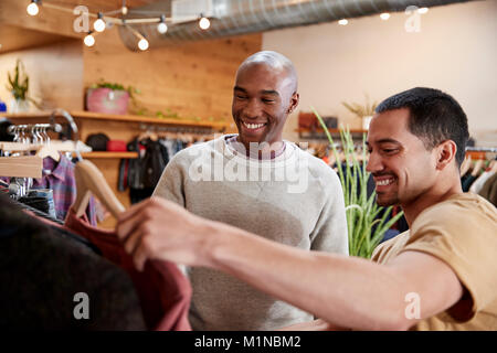 Due amici maschi guardare i vestiti in un negozio di abbigliamento, close up Foto Stock