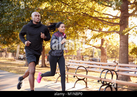 Giovane nero giovane jogging in un parco di Brooklyn, tre quarti di lunghezza Foto Stock