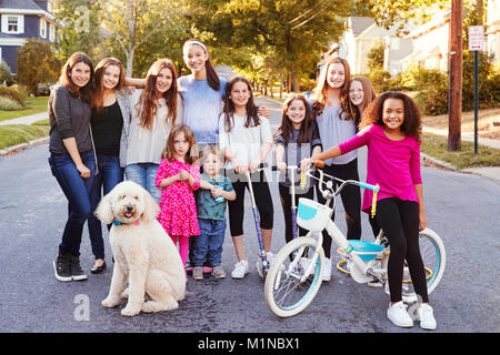 Un gruppo di ragazzi con il cane sorriso a telecamera in una strada residenziale Foto Stock