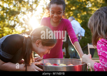 Le giovani ragazze ridere mentre apple bobbing in corrispondenza di una parte del cortile Foto Stock