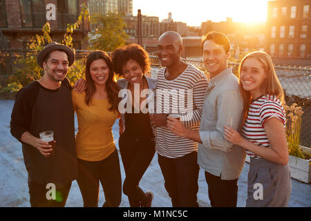 Gli amici a una festa sul tetto in Brooklyn sorridente alla fotocamera Foto Stock