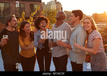 Gli amici a bere e ridere per un party sul tetto di Brooklyn Foto Stock