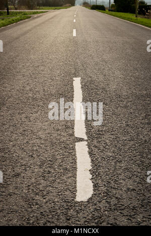 Una linea bianca su una dritta strada asfaltata nel Regno Unito delle paludi con l'orizzonte e Vanishing Point a distanza Foto Stock