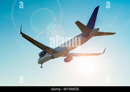 Aeroplano e sunbeam con lens flare effetto sul cielo blu sullo sfondo Foto Stock