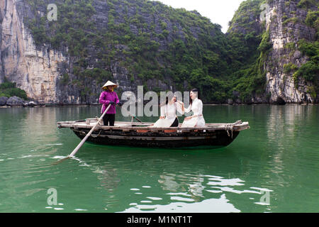 Giovani donne touring su una barca a remi (sampan) nella baia di Halong, Vietnam. Le isolette di calcare e di formazioni rocciose sono diventati un'UNESCO area protetta. Foto Stock