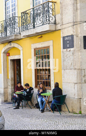 Quattro giovani seduta al di fuori di un piccolo cafe a Lisbona, Portogallo Foto Stock