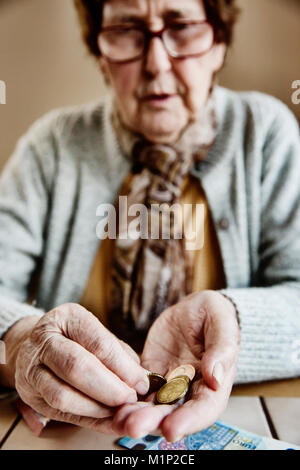 Senior Citizen si siede a tavola e conta il suo denaro,Germania Foto Stock