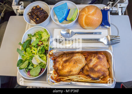 Una cena il pasto a bordo con pasta, pollo, formaggio, burro, cioccolato dolce e pane su un vassoio a bordo di un lungo volo dall'Europa all'America in eco Foto Stock