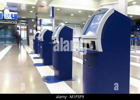 Una linea di auto check-in macchina al momento del check-in contatori area all'interno di un aeroporto greco. Foto Stock