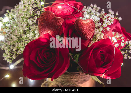 Vista ravvicinata di fiori e rose con cuori rossi in esso e luci cablato che lo attraversano. Foto Stock