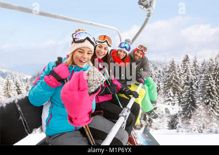 Ragazze con guy in ski lift prendendo foto Foto Stock