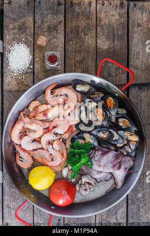 Greggio prodotti a base di pesce in padella per paella su un tavolo di legno, vista dall'alto Foto Stock