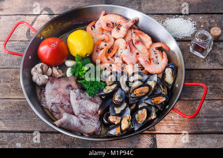 Greggio prodotti a base di pesce in padella per paella su un tavolo di legno Foto Stock