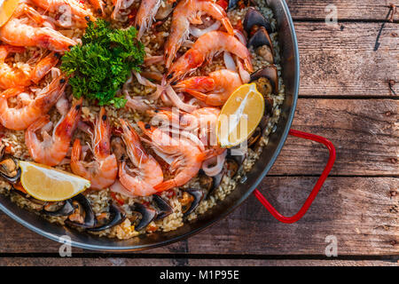 Tradizionale paella di frutti di mare in padella su una tavola di legno vecchio tavolo, vista dall'alto Foto Stock