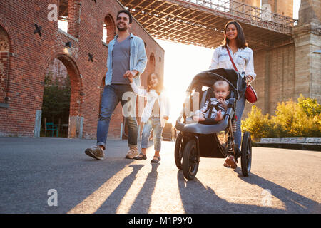 Famiglia giovane con due figlie a piedi su una strada Foto Stock