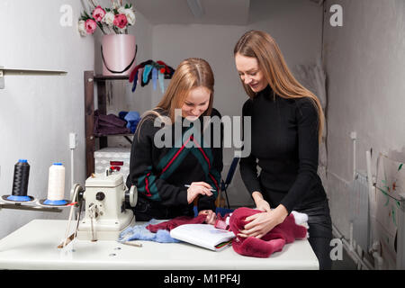 Due giovani donne furriers stanno discutendo di come propriamente tagliato pelliccia naturale per rendere una donna di pelliccia. Il processo per la fabbricazione di una donna di pelliccia Foto Stock