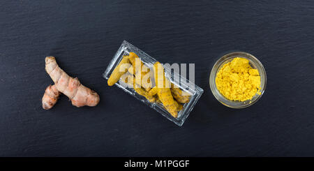 Freschi e Secchi o di curcuma curcumina radici e polvere su sfondo nero. Vista superiore Foto Stock