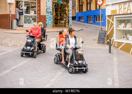 Le donne che utilizzano la mobilità noleggiato scooter in strada di Benidorm, Spagna Foto Stock
