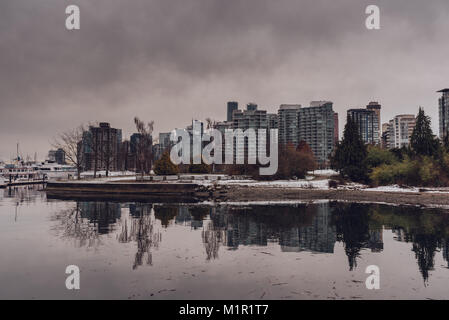 Vista del porto e della città di Vancouver (BC, Canada) grattacieli con riflessi nell'acqua in un nuvoloso giorno d'inverno. Foto Stock