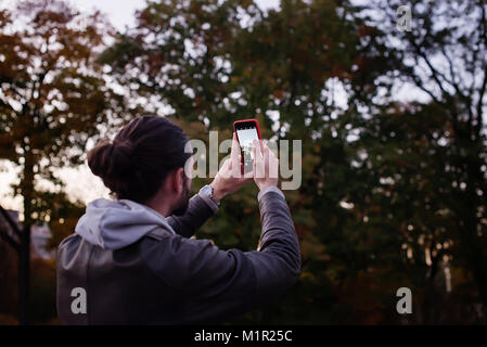 Fotografo urbano con telefono mobila fare foto su street.Foto e chiavi di basso e con una messa a fuoco morbida. Foto Stock