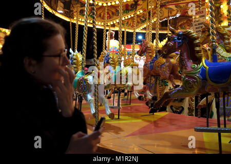 Una donna orologi una giostra, rotonda, o merry-go-round a Hyde Park Winter Wonderland Foto Stock