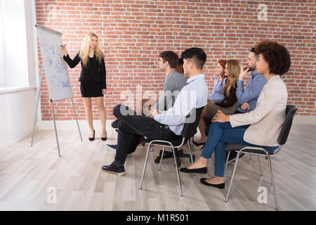 Giovane imprenditrice dando la presentazione al suo collega in ufficio Foto Stock