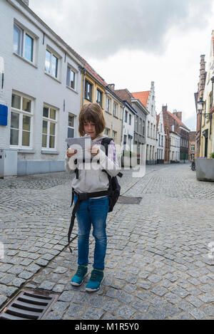 Clueless bambina guardando una mappa per orientare se stessa in un vecchio centro storico della città medievale di Bruges, Belgio Foto Stock